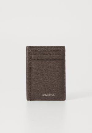 Billetera de cuero marrón con un acabado texturizado, que cuenta con cuatro ranuras para tarjetas y un logotipo en relieve. Tamaño compacto para facilitar su transporte.