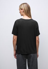 Zwarte korte mouwen t-shirt van zacht materiaal, met een klassieke ronde hals en een comfortabele pasvorm, gekenmerkt door een gladde textuur en een eenvoudig ontwerp.
