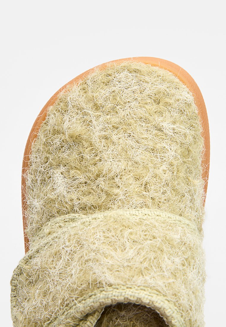 Zachte, lichtgroene, fuzzy slide-sandaal met een gestructureerde bovenkant, voorzien van een brede band en een dikke, eenvoudige zool in lichtbruin.