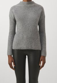 Maglione grigio in maglia a coste con collo alto, maniche lunghe e vestibilità comoda, abbinato a pantaloni neri aderenti. Aspetto testurizzato e accogliente.