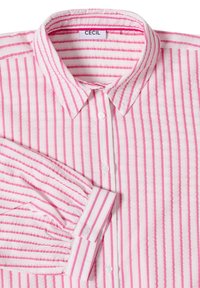 Chemise blanche à manches longues avec des rayures verticales roses, fermeture par boutons sur le devant et un col pointu, étiquette "CECIL".