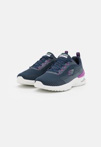 Zapatillas deportivas azul marino con parte superior de malla transpirable, suela blanca y acentos morados, que presentan un diseño texturizado y un sistema de cordones.