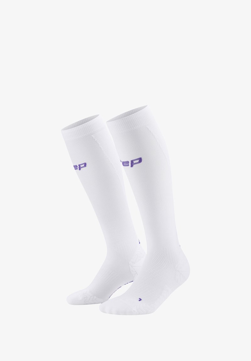 Weiße Kompressionssocken mit einem strukturierten Design, geripptem Material und einem lila Logo. Knielange Socken mit verstärkter Zehen- und Ferse.