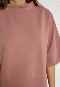 Pullover color rosa con collo alto, maniche corte e vestibilità comoda. Realizzato in morbido e liscio tessuto misto cotone.