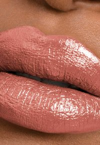 Couleur de lèvres rose avec une finition brillante, présentant une surface texturée et un volume prononcé, sur un fond de peau lisse.