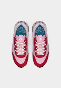 Ζευγάρι ροζ και κόκκινα αθλητικά παπούτσια Converse με λευκά κορδόνια, λογότυπο της κεφαλής βέλους και μπλε εσωτερικές σόλες με κυκλικό σχέδιο, σε θέα από πάνω.