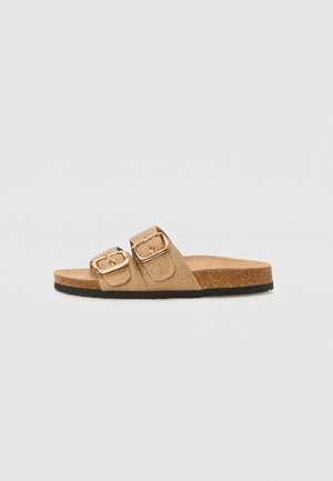 Sandalias tipo chancla beige con dos correas ajustables, hebillas metálicas, parte superior texturizada y plantilla de corcho, con una suela exterior de goma negra.