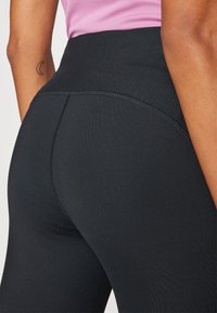Hoge zwarte leggings met een geribde tailleband, met een gladde textuur, strak aansluitend ontwerp en minimale stikdetails.