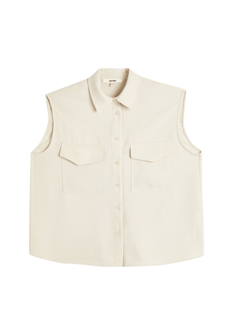 Blusa senza maniche di un beige chiaro con colletto, chiusura frontale con bottoni e due tasche sul petto. Tessuto liscio e vestibilità comoda.