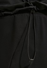 Κοντινό πλάνο μαύρου υφάσματος με κορδόνι και πλαστικό κλιπ σε μέση ρούχου ή κουκούλα.