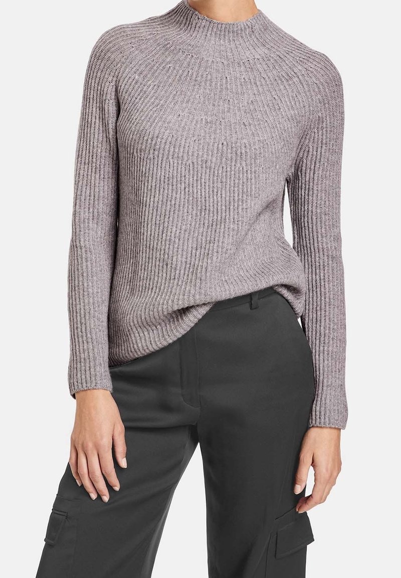 Maglione a collo alto in maglia a costine di un grigio chiaro. Caratterizzato da maniche lunghe e una vestibilità ampia, abbinato a pantaloni cargo scuri.