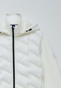 White puffer jacket featuring a quilted design, a front zipper, and an attached hood with black toggles, displayed against a neutral background.