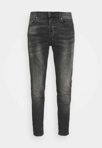 Jeans de mezclilla negra ajustados con una sutil textura desgastada, diseño de cinco bolsillos, detalles metálicos y costuras en los bolsillos.