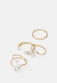 Set di anelli in tono oro con perle bianche. Tre anelli hanno design lisci e rotondi, mentre uno è una semplice fede. Superfici texturizzate e lucidate.
