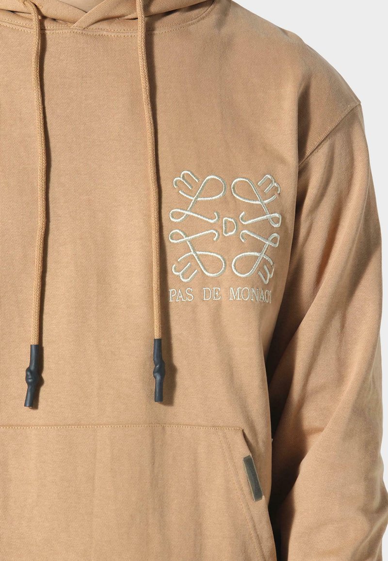 Hooded sweatshirt van lichtbruin stof met een voorzak, gestructureerd garen, verstelbare trekkoord en geborduurd logo op de borst.