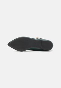 Flat shoe with a smooth green leather upper, pointed toe, black rubber sole, and a gold buckle accent on the side.