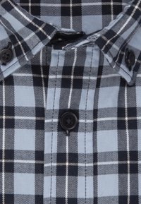 Blå och svart rutigt skjorta med nerknäppt krage, två svarta knappar och en bomullstextur med kontrasterande vita rutlinjer.