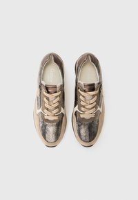 Un paio di sneakers metallizzate bronzo e beige con lacci beige e zip laterali, viste dall'alto su uno sfondo bianco semplice.