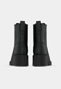 Mustad pahkluu saapad siledast nahast, elastsete küljeosade ja robustse kontsaga. Varustatud tõmblukuga hõlpsaks jalga panekuks.