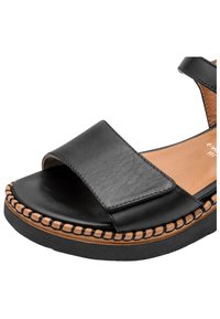 Sandale en cuir noir avec large bride avant, semelle plateforme cousue couleur beige et bride de cheville avec fermeture à boucle.