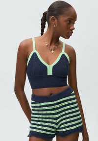 Námornícky modrý a mätovo zelený pletený crop top s hlbokým V-výstrihom a zodpovedajúcimi pásikavými šortkami s vysokým pásom, ktoré majú volánové okraje a otvorené pletené detaily.