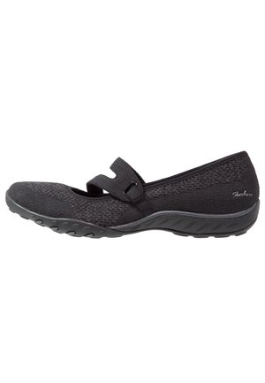 Czarny but w stylu Skechers Mary Jane z teksturowaną tkaniną, regulowanym paskiem, gumową podeszwą i niskim obcasem.