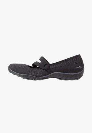 Czarny but w stylu Skechers Mary Jane z teksturowaną tkaniną, regulowanym paskiem, gumową podeszwą i niskim obcasem.