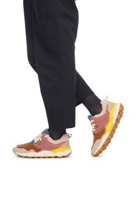 Zapatillas multicolores con materiales texturizados en marrón, rosa y azul, cordones blancos y una entresuela amarilla. Suela exterior gruesa de goma.