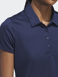 Navy zils polo krekls ar tradicionālo apkakli, īsām piedurknēm un pogu aizdari. Materiāls izskatās gluds ar maigu spīdumu.