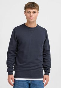 Marineblaue Sweatshirt mit geripptem Rundhalsausschnitt, langen Ärmeln und strukturiertem Stoff. Verfügt über einen taillierten Saum und ein dezentes Logo am Bund.