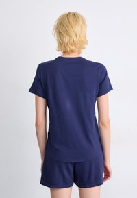 T-shirt en coton bleu marine à manches courtes et encolure ronde, associé à un short assorti, vu de dos. Texture lisse.