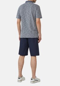 Polo shirt in blauw en grijs melange, gecombineerd met marineblauwe shorts. Beschikt over een kraag en korte mouwen, aangevuld met lichte sneakers.