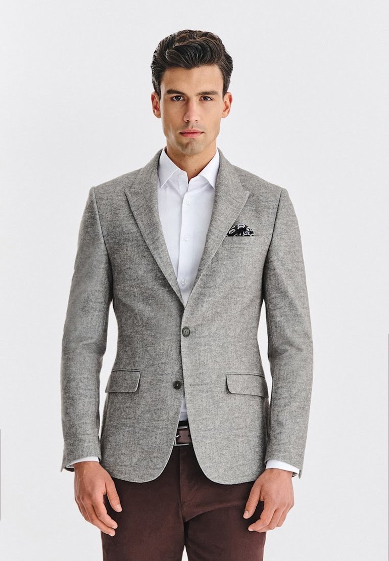 Jasnoszary żakiet wykonany z teksturowanej tkaniny, z klapami, dwoma przednimi kieszeniami oraz czarno-białą chusteczką w kieszeni.