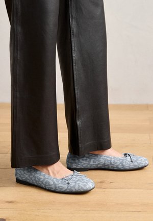 Jasnoniebieskie baleriny z teksturowanym wzorem w panterkę, z kokardą na czubku i płaską podeszwą, w połączeniu z czarnymi skórzanymi spodniami.