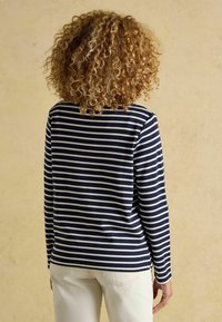 Námornícky modré a biele pruhované tričko s dlhými rukávmi, s okrúhlym výstrihom a voľným strihom. Tkanina pôsobí mäkko s hladkým povrchom.