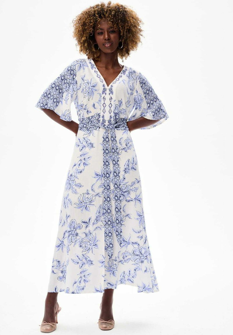 Maxi jurk met bloemenprint in wit en blauw, gekenmerkt door korte brede mouwen, een V-hals en een cinched taille. Vloeiende stof met gedetailleerde patronen.