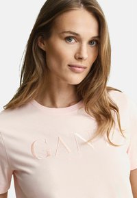 Helles rosa Baumwoll-T-Shirt mit geprägtem Text "GANT NEW HAVEN" auf der Vorderseite, klassischem Rundhalsausschnitt und kurzen Ärmeln.
