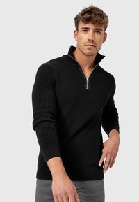Sort ribbet pullover med kvart-zip krave og lange ærmer, der har et struktureret strikmønster og en lige kant.