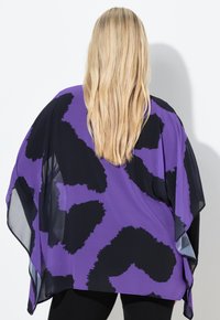 Violetti ja musta kuvioitu yläosa, jossa on väljähkö malli, kevyt laskeutuvuus ja läpikuultavat yksityiskohdat reunoilla.