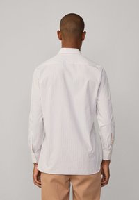 Chemise à rayures blanche avec des rayures orange clair et bleues, manches longues, poignets boutonés et col classique.