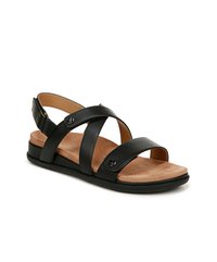 Sandalo in pelle nera con cinturini incrociati, soletta imbottita beige e suola nera bassa. Presenta decorazioni con accessori rotondi.