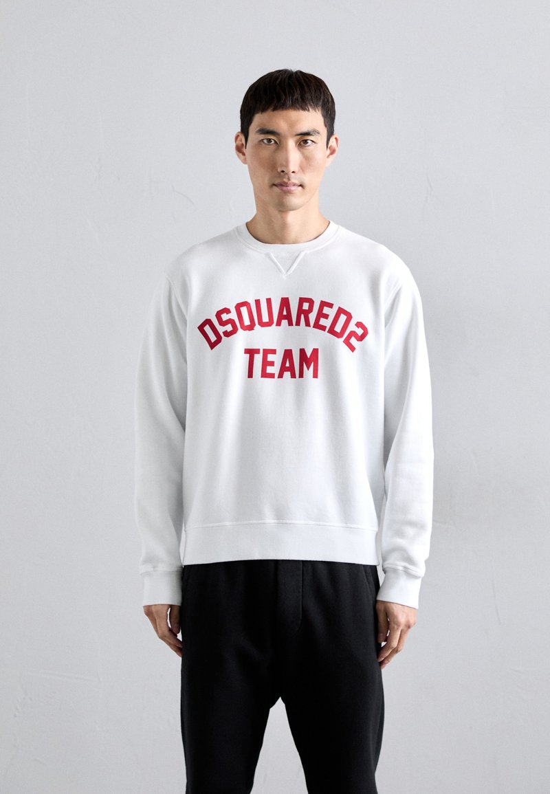 Felpa bianca in cotone, con testo curvo rosso "DSQUARED2 TEAM" sulla parte anteriore. Vestibilità ampia con polsini e orlo inferiore a costine.