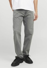 Grijze denim jeans met een rechte pasvorm, lichte vervaging en contraststiksel. Gecombineerd met zwarte veterschoenen en een wit oversized t-shirt.