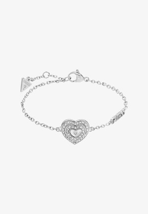 Bracelet chaîne en argent avec un pendentif en forme de cœur orné de cristaux et un fermoir mousqueton, avec une petite étiquette logo triangulaire.