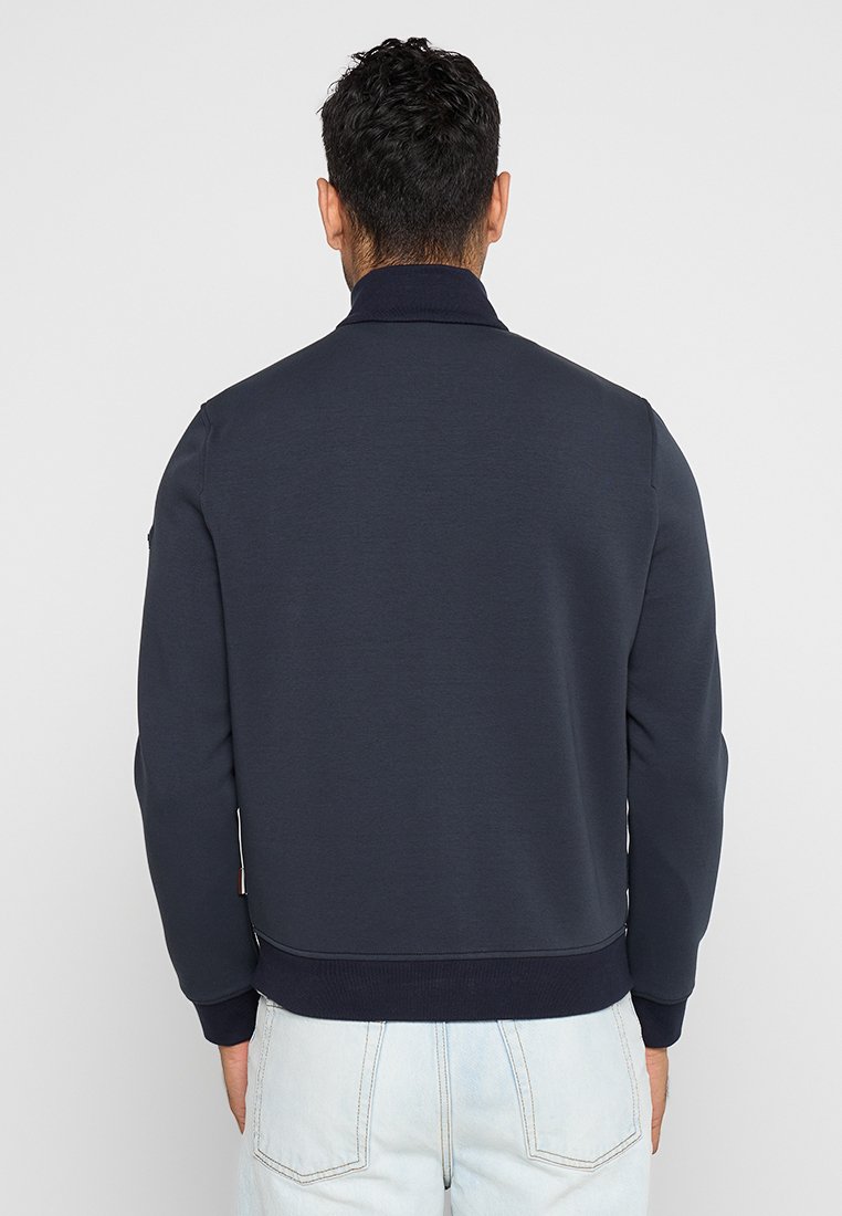 Felpa blu navy realizzata in tessuto morbido, con colletto, polsini e orlo a costine, con cuciture minime e una texture liscia.