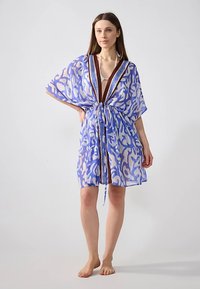 Genomskinlig, lätt kimono i blå nyanser med abstrakt mönster. Har djup urringning, knytning i midjan och lösa, flödande ärmar.