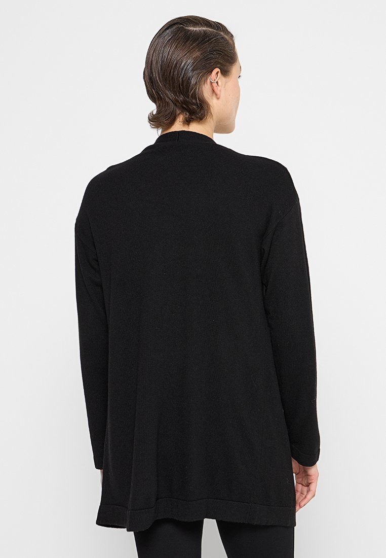 Czarny kardigan z długim rękawem o luźnym kroju, z prostym dołem i ściągaczami na mankietach. Wykonany z miękkiego, teksturowanego materiału.
