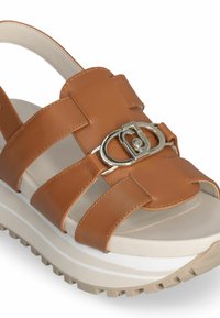 Brown leather sandal with multiple wide straps, silver hardware accent, white and beige platform sole, textured tread for grip.