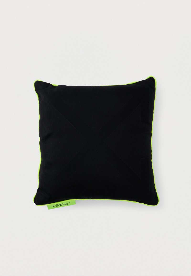 Coussin carré noir avec des bords vert néon et une petite étiquette verte néon portant l'inscription « Off-White » sur un fond blanc.
