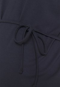 Dark navy fabric with a soft texture, featuring a tie at the waist. The garment has smooth stitching and a relaxed design.